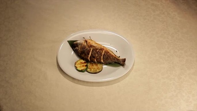 库克将鱼放在蔬菜装饰的盘子上
