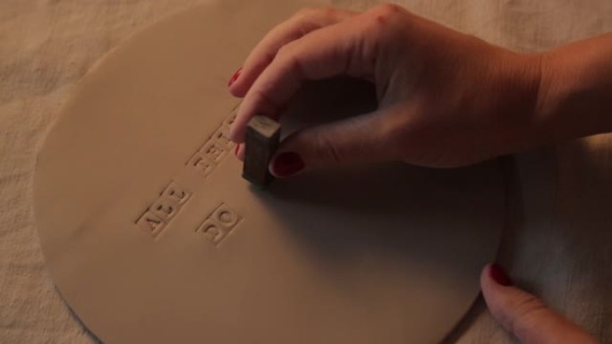 在车间的粘土板上印刷字母。手工陶瓷制作的装饰餐具特写。