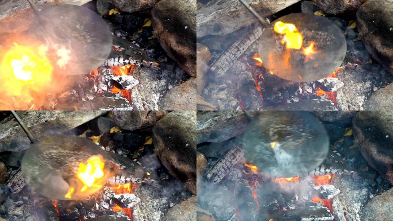 朋友们在户外野营时在篝火上做传统的煎饼