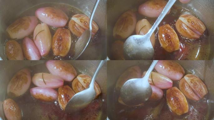 慢动作高角度勺子搅拌整个葱在不锈钢锅中的热香醋中炖