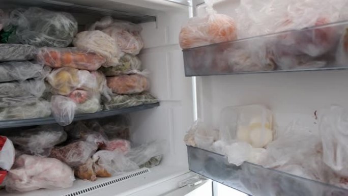 冷冻食品在冰箱的架子上，冷冻室和冷冻食品，一个人从冷冻室拿食物，