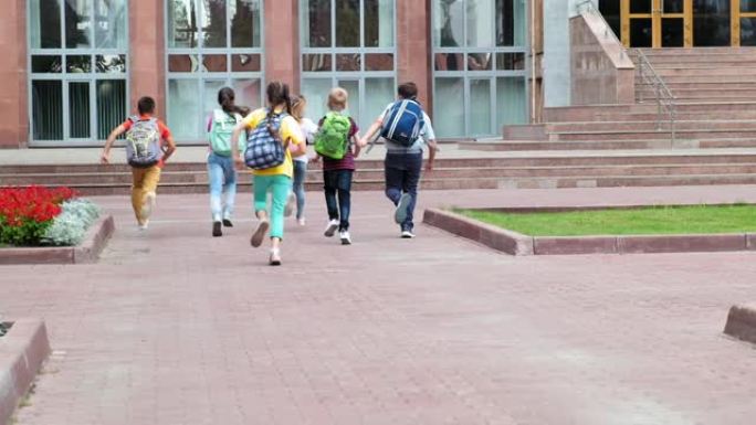 带着书包的低年级学生跑向学校大楼