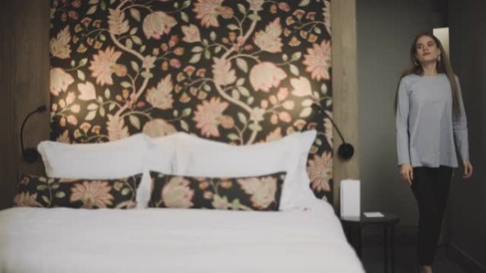 漂亮女人进入豪华酒店的房间。放松的女人在酒店跳床