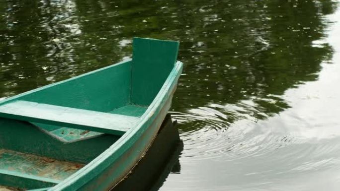 绿色木船在水面上荡漾，水面上荡起涟漪。