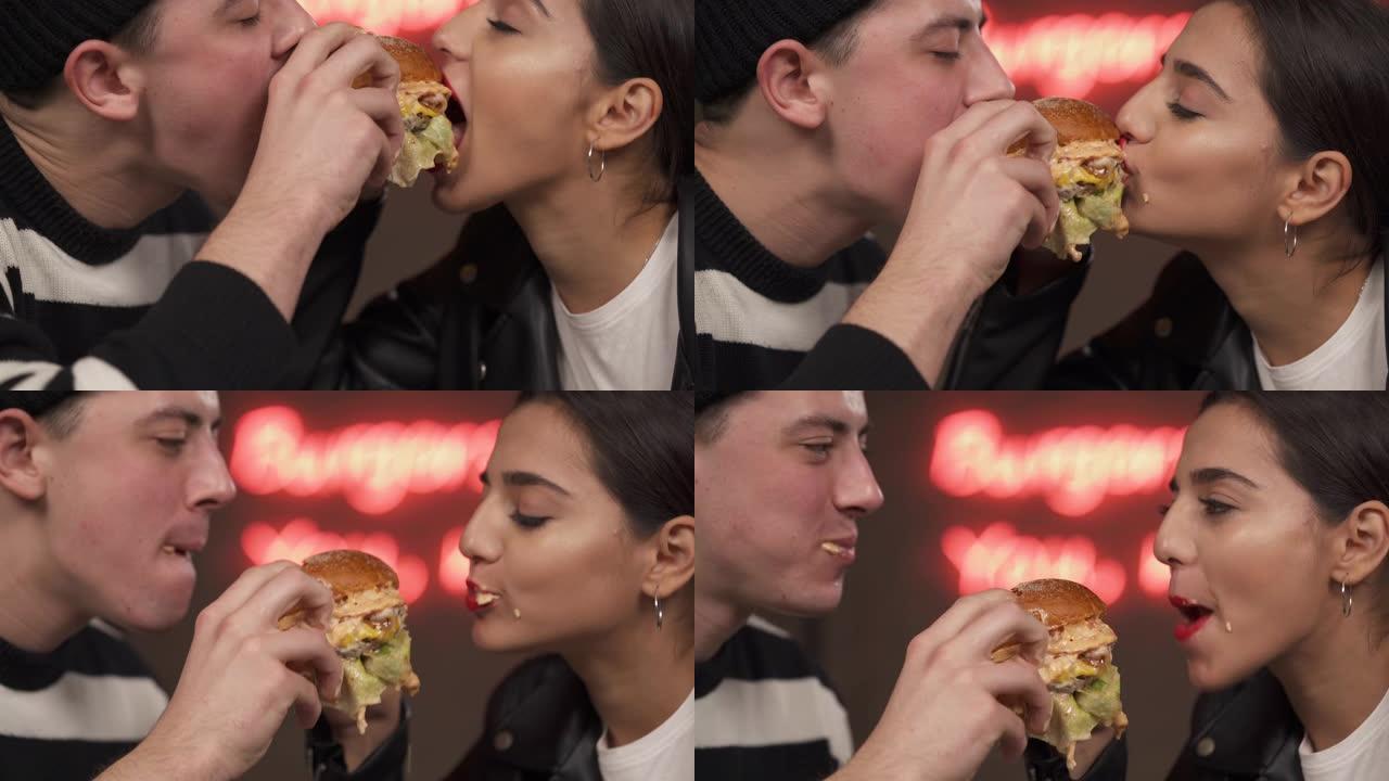 美丽的年轻夫妇一起吃饭。恋人从侧面一起吃汉堡。浪漫约会概念