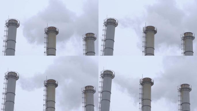 灰色多云天空背景下的工业管道烟雾。灰蒙蒙的天空映衬着植物的烟囱冒烟。环境污染。全球变暖。空气排放。特
