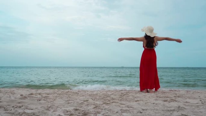 自由女人在海上海滩上举起手臂，随风而行