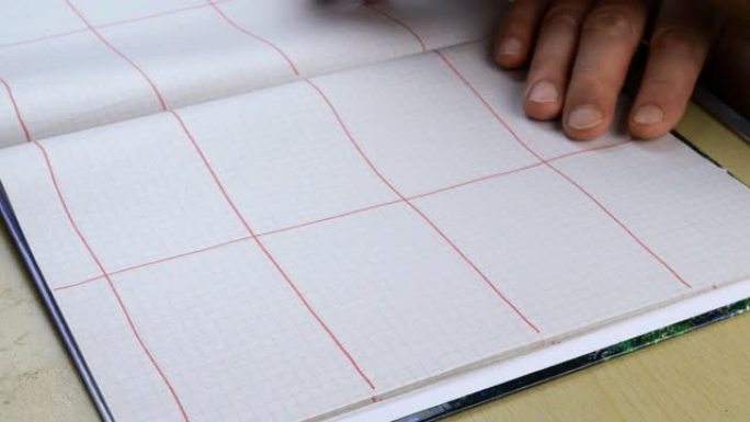 人用红色铅笔在笔记本上绘制图式。