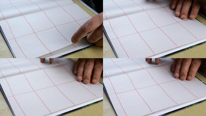 人用红色铅笔在笔记本上绘制图式。