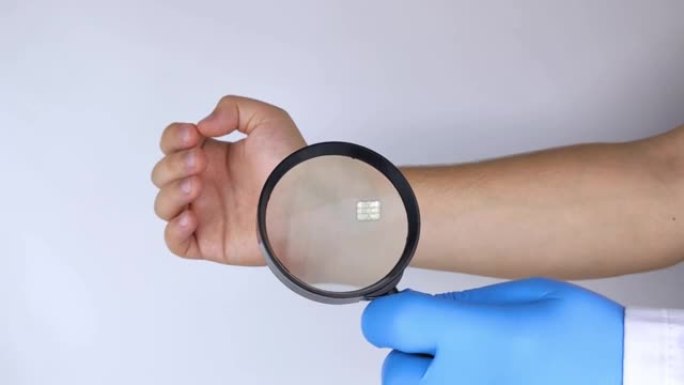 整容外科医生通过放大镜用生物芯片检查患者的手。控制论、生物技术和高科技未来的概念。孤立在白色上