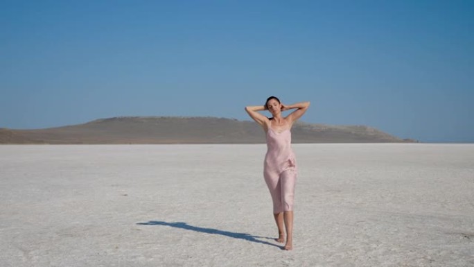 穿着粉红色连衣裙的女人走过克里米亚的盐沙漠