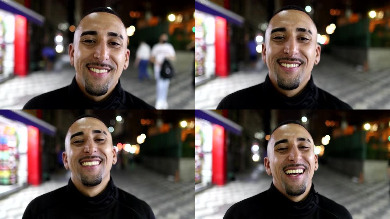 巴西西班牙裔男子晚上在城市的镜头前微笑