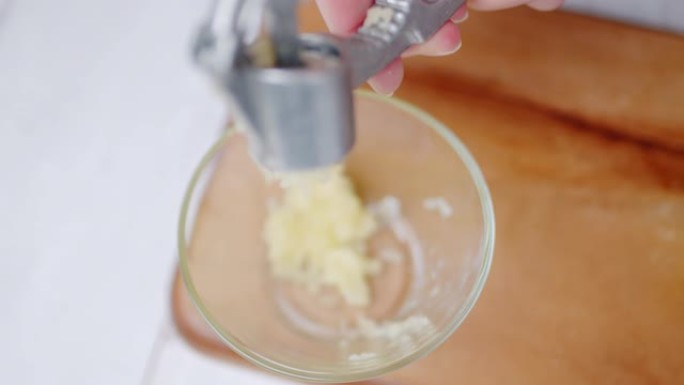 用4K大蒜压榨机压碎大瓣大蒜的特写镜头。使用大蒜压榨机，樱桃果皮或胡桃夹子工具以慢动作切碎大蒜的概念