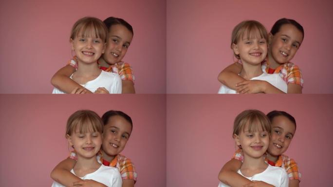 两个粉红色背景的小女孩。朋友。兴奋的幼儿