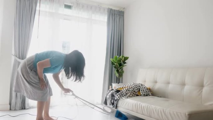 亚洲女性在家使用真空吸尘器清洁，生活方式理念。