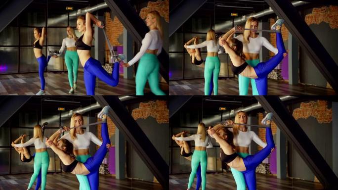 个人健身教练的倾斜镜头帮助女性客户在伸展工作室的个人课上做舞蹈主姿势