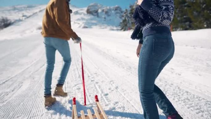 年轻夫妇在拉雪橇上坡时赛车，享受和亲吻