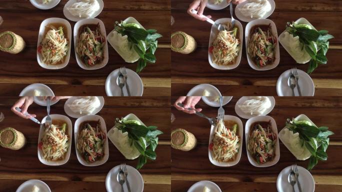 泰国菜餐桌的俯视图拍摄: 吃东北食物 (SOM TUM-辛辣木瓜沙拉，糯米饭，木桌上的烤猪肉沙拉。本