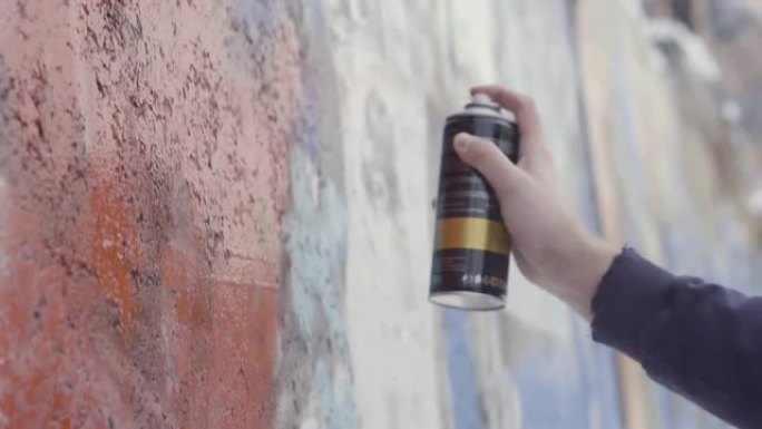 特写艺术家在墙上画画和喷漆，街头艺术概念。行动。在混凝土墙上涂鸦的过程中，男人的手的侧视图
