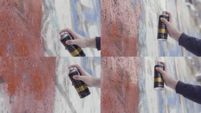 特写艺术家在墙上画画和喷漆，街头艺术概念。行动。在混凝土墙上涂鸦的过程中，男人的手的侧视图