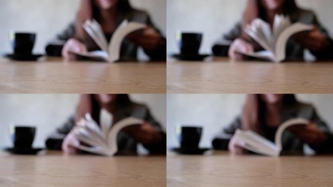一个女人在木桌上打开和看书的模糊