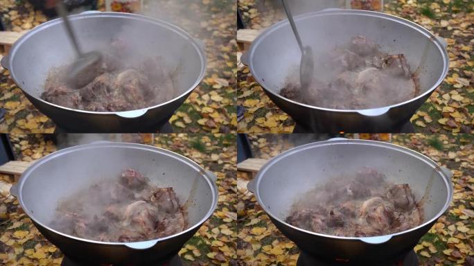 把棕色的肉扔进一个大平底锅里。户外抓饭烹饪肉的特写