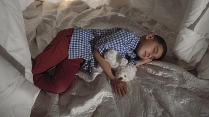 可爱的小男孩睡在毯子做成的玩具屋里