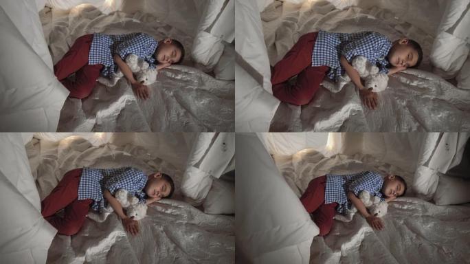 可爱的小男孩睡在毯子做成的玩具屋里