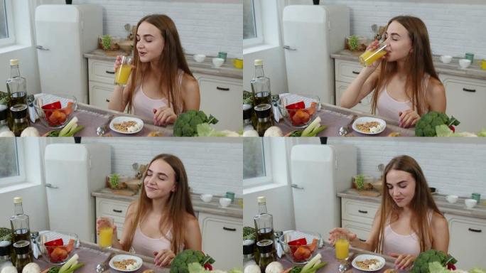 女孩吃生芽荞麦和坚果，在厨房喝橙汁。减肥和饮食