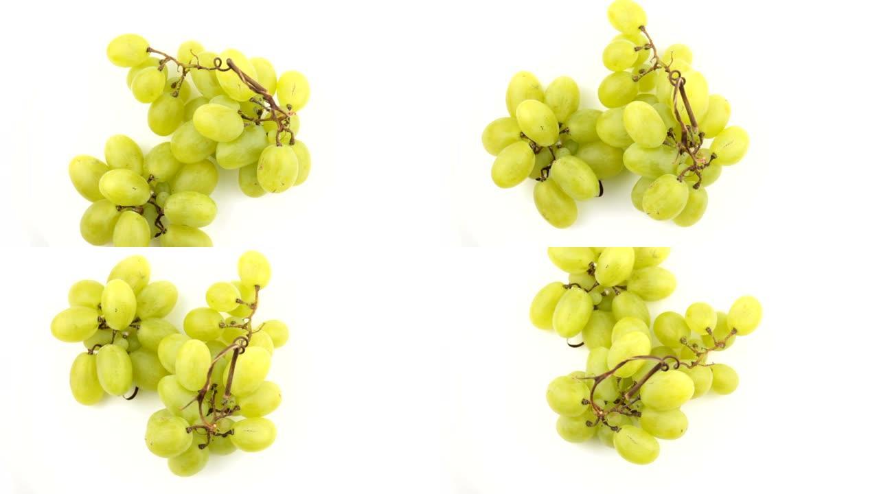 成熟多汁的葡萄在盘子上旋转。一串白葡萄的特写。新鲜一束多汁的葡萄在白色背景上旋转。