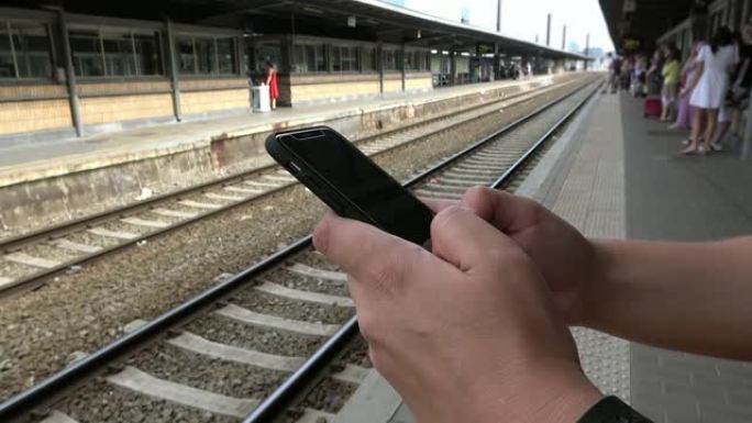 4K.在等待火车到达时使用智能手机的人