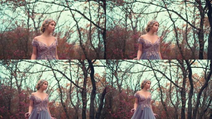 美丽的年轻金发公主站在紫色郁郁葱葱的连衣裙。中世纪迷人女王的复古时尚。皇冠上迷人的女皇。秋园背景，黑
