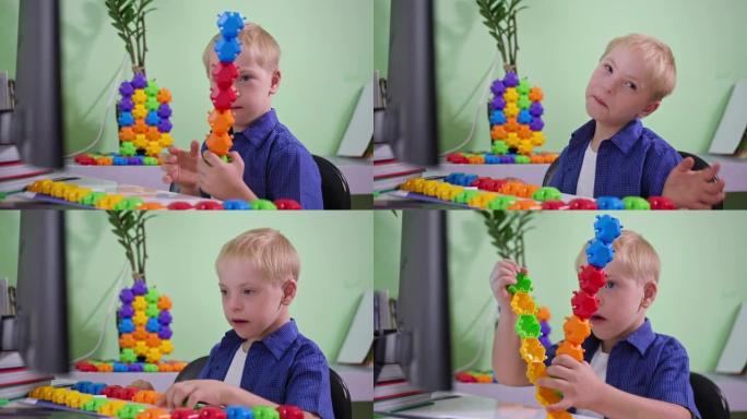 家庭娱乐，患有唐氏综合症的孩子坐在桌子旁玩彩色的构造器，并将玩具显示在计算机屏幕上