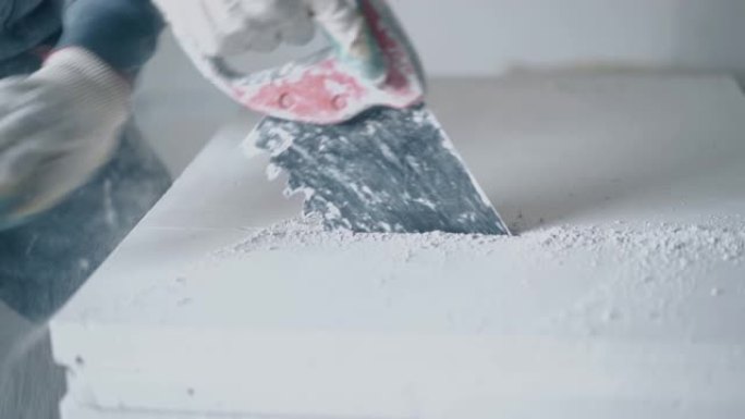 熟练工人拿着锯和切割大的白色石膏板