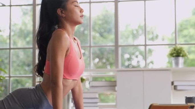 亚洲女性在家锻炼高眼镜蛇瑜伽姿势。在家在线学习