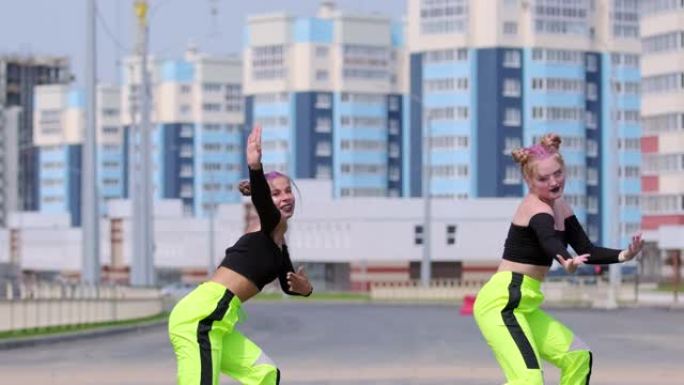 年轻开朗的女性二重奏在城市户外跳舞自由风格的街舞，嘻哈舞蹈。慢动作