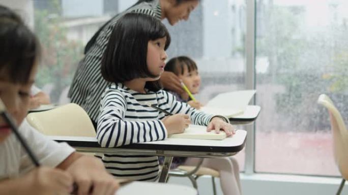 亚洲儿童在学校一起学习和写作教室。教育概念。
