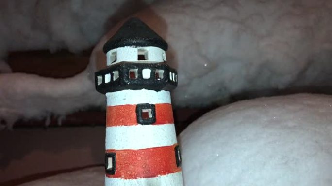 红白玩具灯塔被大白雪包围，夜晚有烛光