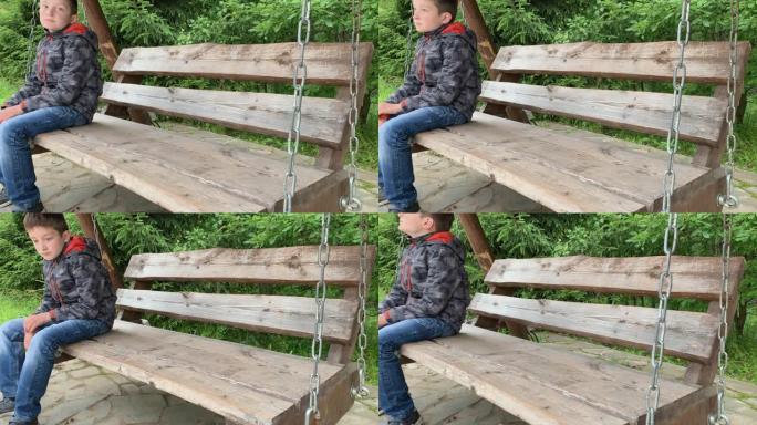 一个悲伤的男孩坐在空荡荡的秋千上，想念他的母亲，他正在公园里等他的母亲