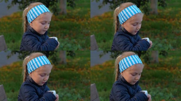 孩子在公园户外使用智能手表。在智能手机上通过vdeo通话的孩子。女学生在浏览互联网的手表上使用触摸屏