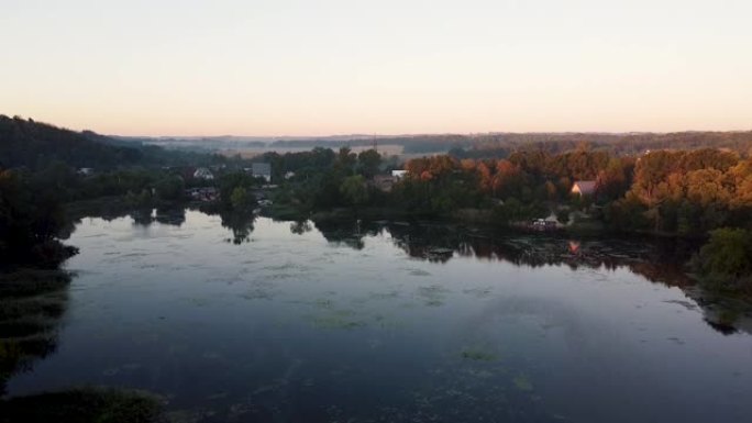 夏季乡村景观的鸟瞰图。松树和黄色的秋天森林。日出，黎明，雾蒙蒙的清晨在一个小渔村。美丽的河湾或湖泊