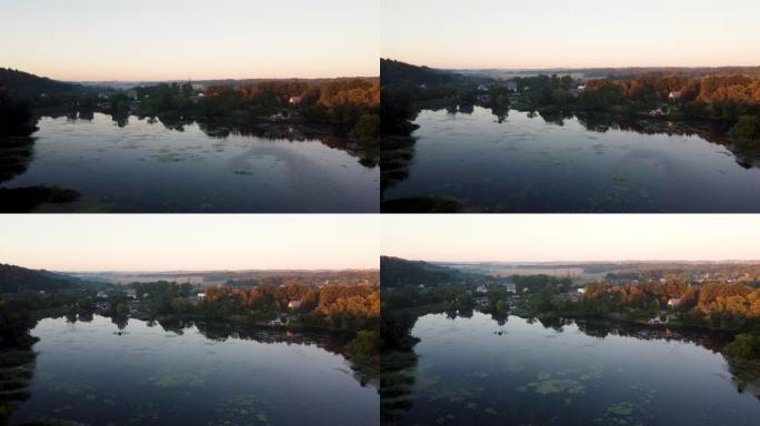夏季乡村景观的鸟瞰图。松树和黄色的秋天森林。日出，黎明，雾蒙蒙的清晨在一个小渔村。美丽的河湾或湖泊