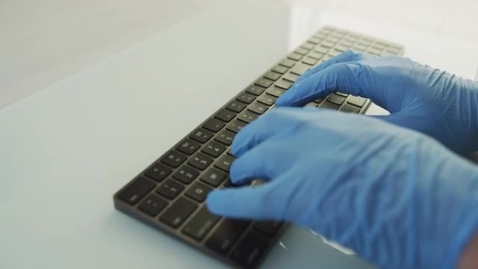 医生或护士或办公室工作人员在工作时使用保护手套在计算机pc上的键盘上书写，以阻止冠状病毒，新型冠状病