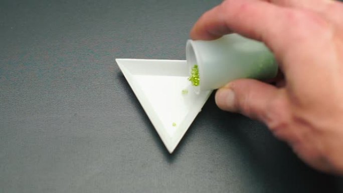 将绿色珠子倒入珠宝作坊的三角板中。