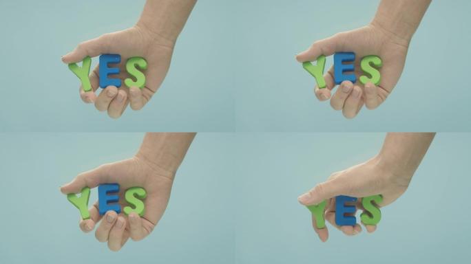 手在水下慢慢移动，握着 “是” 字，这个字是用绿色和蓝色的塑料字母制成的。