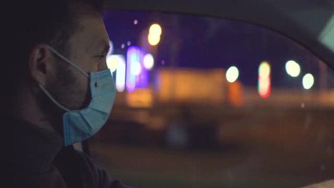戴着医用面具的男人开车穿过夜城