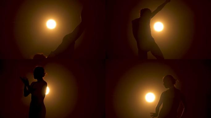 剪影一位优雅的芭蕾舞演员穿着黑色连衣裙表演古典芭蕾舞剧的舞蹈元素。在工作室黄色聚光灯下的黑暗中拍摄。