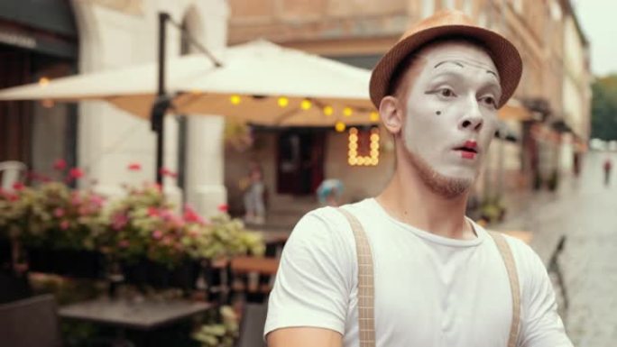 否认，年轻英俊的哑剧演员正在咖啡馆附近的街上表演。