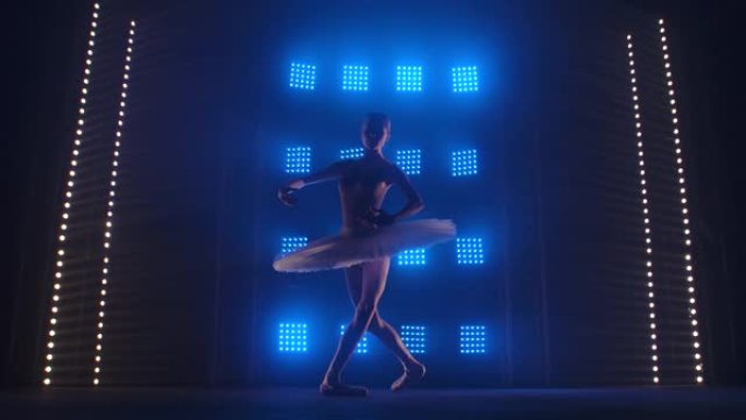 漂亮的芭蕾舞演员优雅地跳舞。演出前的芭蕾彩排。芭蕾舞女演员穿着舞台服装做旋转木马。剪影。带烟雾和蓝色