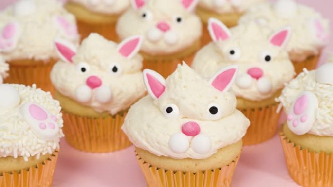 粉色背景的复活节兔子纸杯蛋糕。